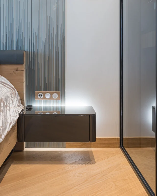 Smoked mirror sliding door with a black profile beside a bed and a floating bedside table