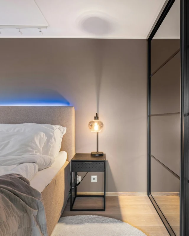 Bedroom with Smoked mirror sliding doors in black profiles beside the bed