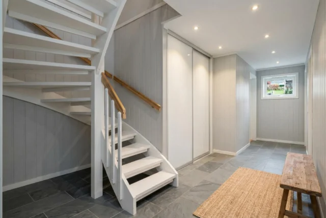 Hallway beside a white staircase with white sliding wardrobe doors