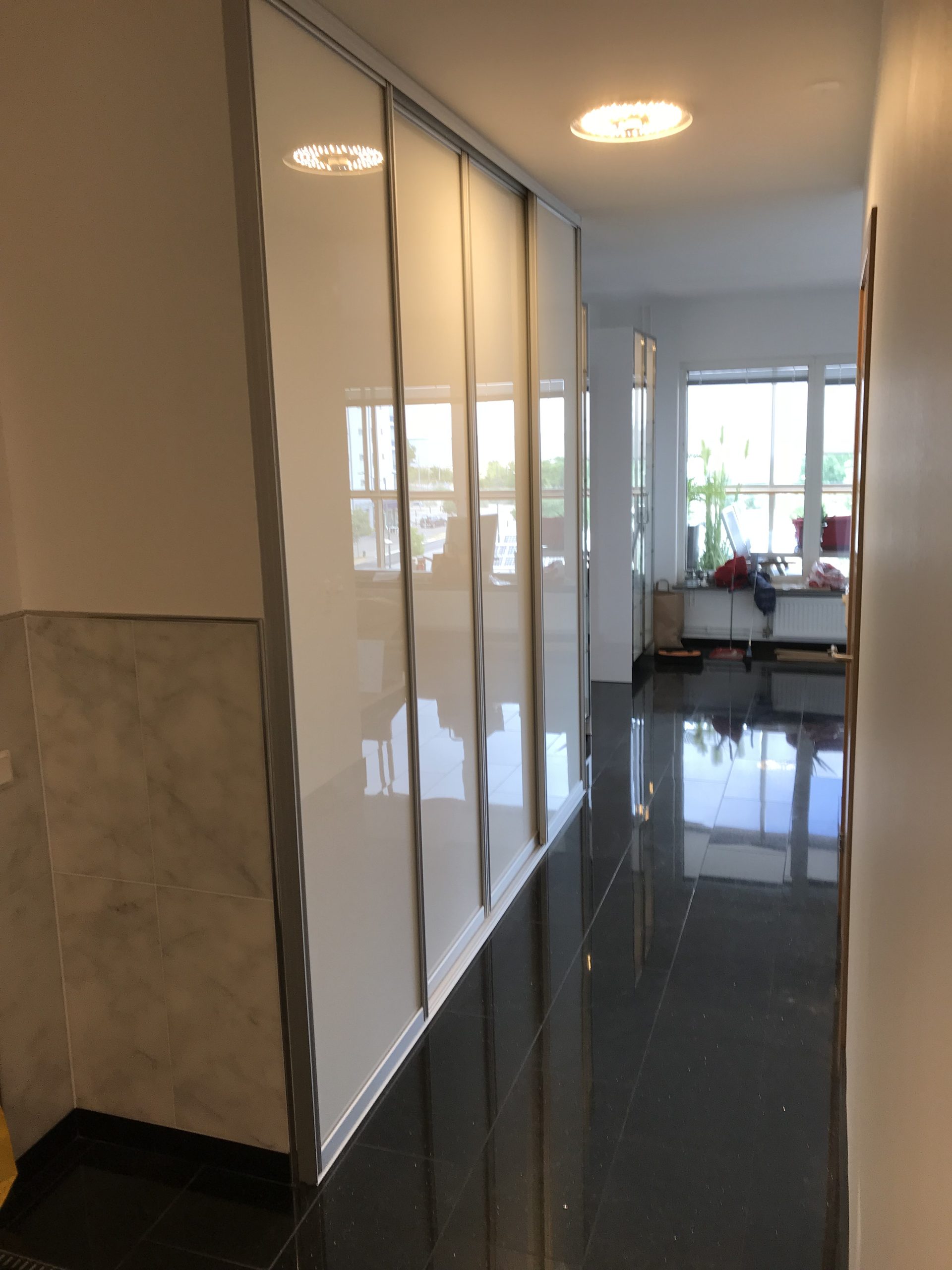 White sliding doors along a long glossy hallway
