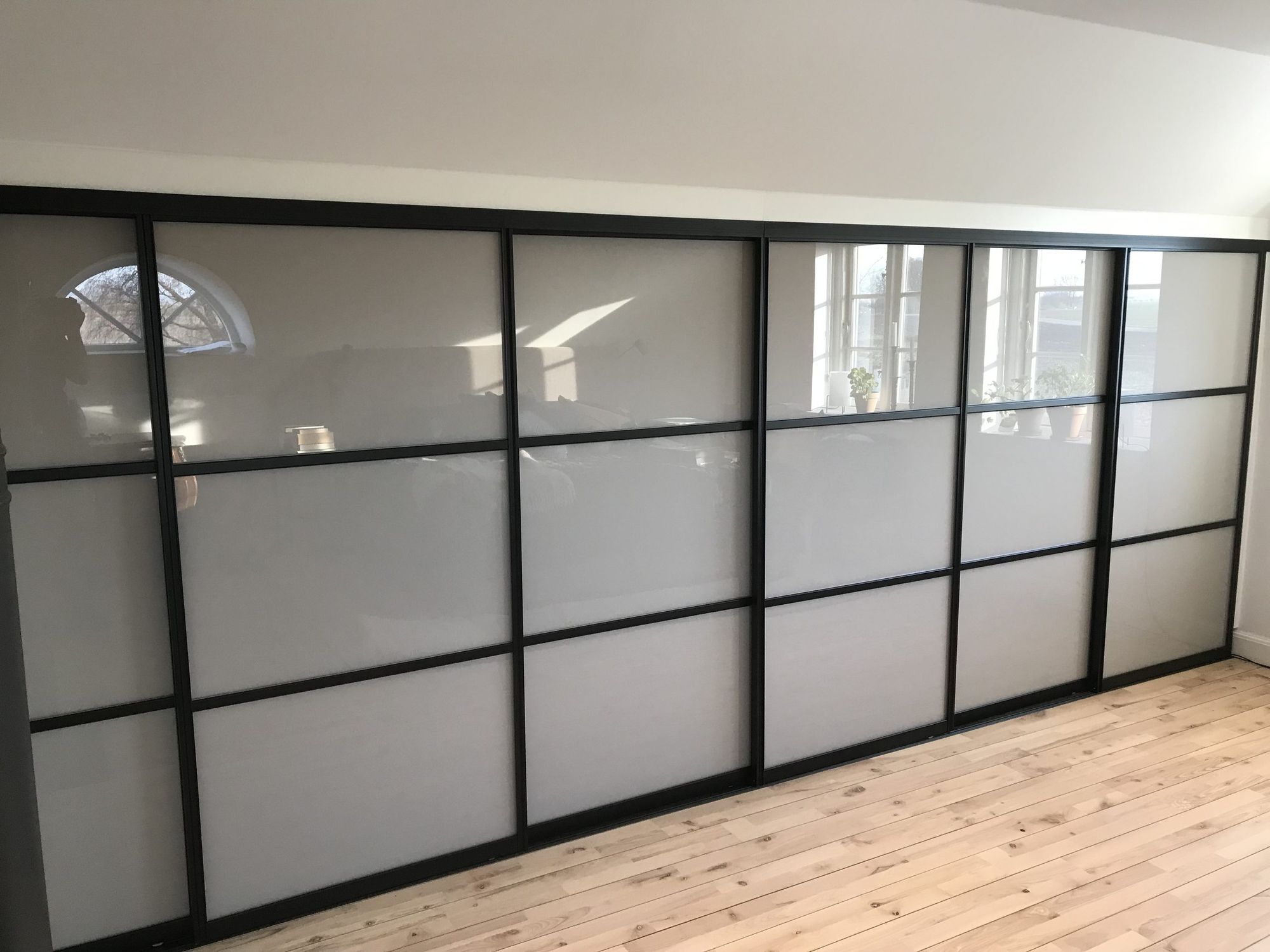 Wardrobe wall with frosted glass doors in black frames
