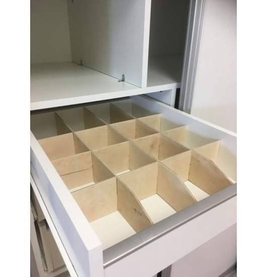 Open drawer with a wooden grid of compartments.