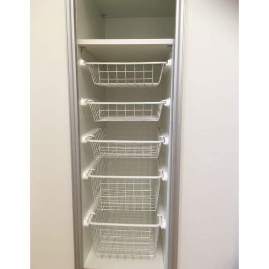 Five white wire baskets stacked in a narrow wardrobe section.