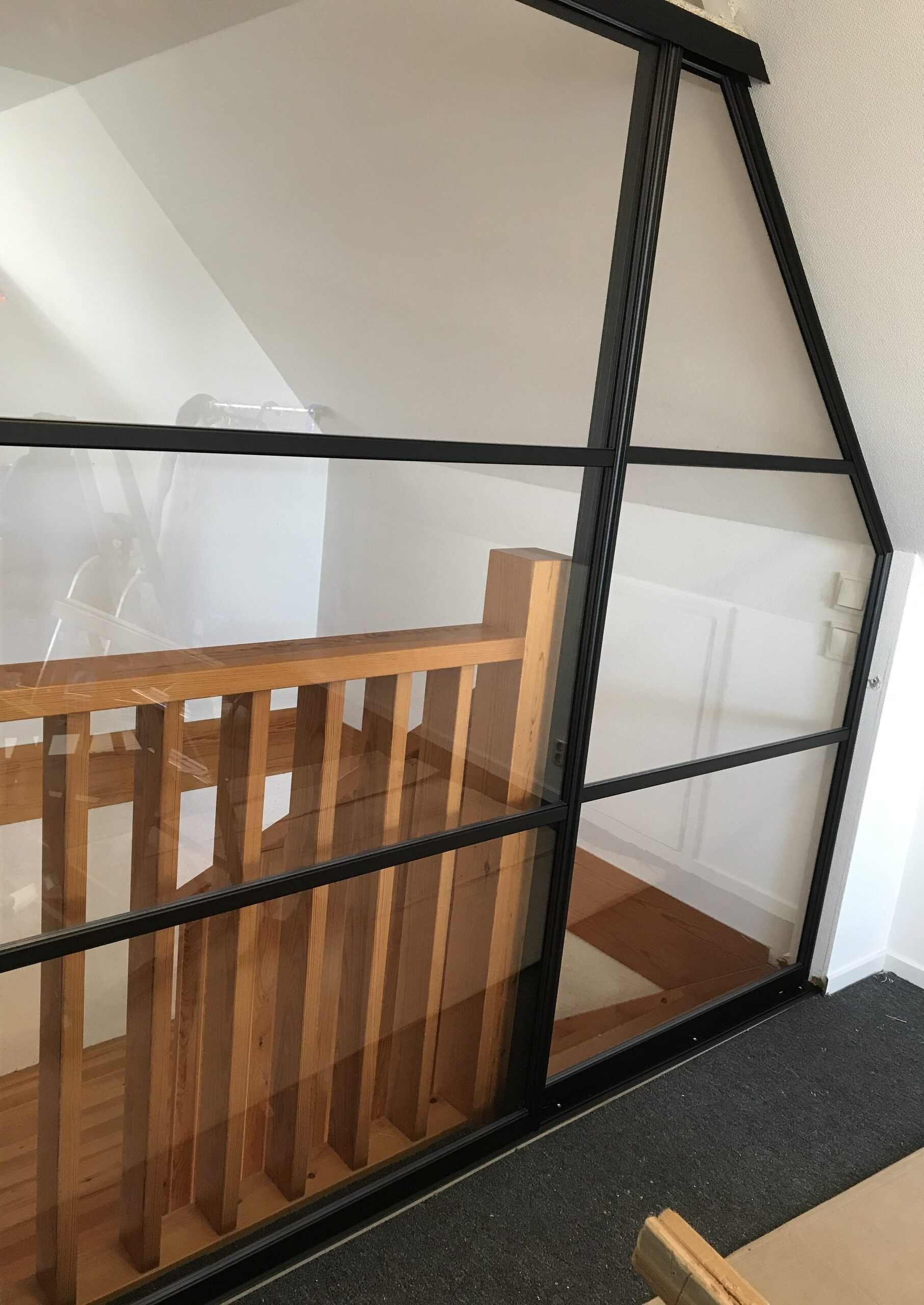 Same stairwell, wood handrail behind the glass